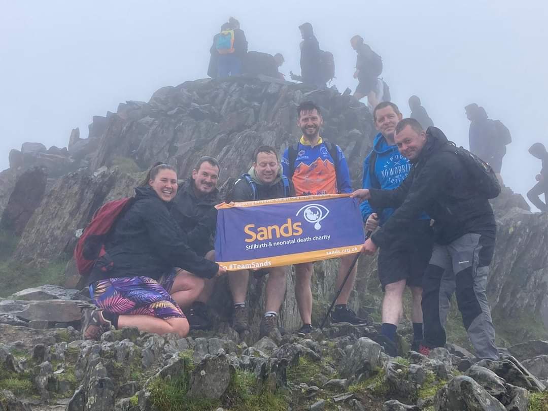 Nikyla and friends on a rocky hill holding a banner for the charity Sands